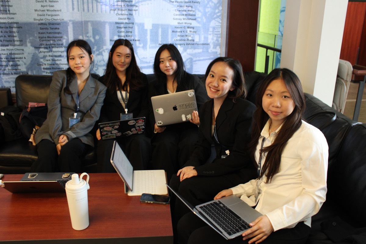 Five Momentum participants seated together with laptops in a campus lounge